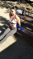 A woman working out outside using a picnic table