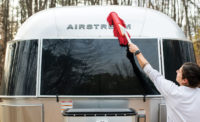 A man using a California Car Duster to clean the outside of an Airstream