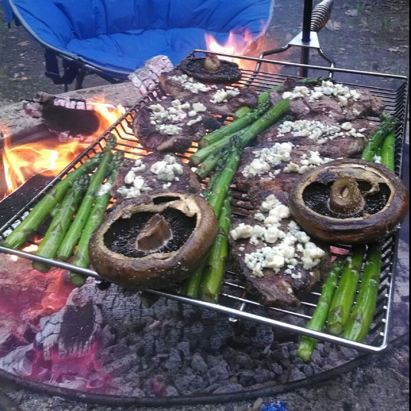 Food Being Cooked Over Fire With Stake And Grill Set